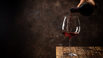 Rotwein wird langsam in ein grosses Burgunderglas eingeschenkt